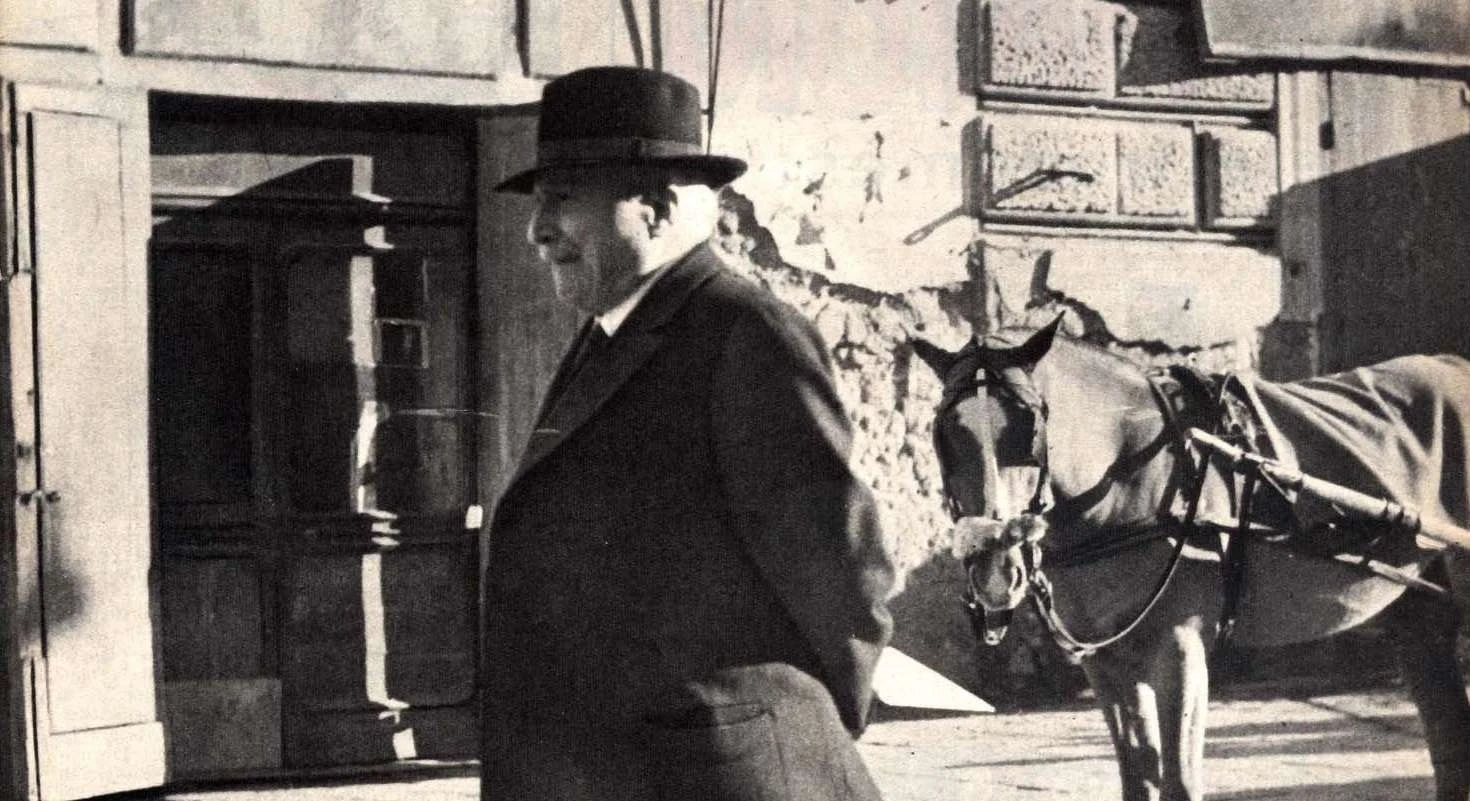 عکس سیاه و سفید انریکو دی نیکولا در حال راه رفتن در یک روز آفتابی.