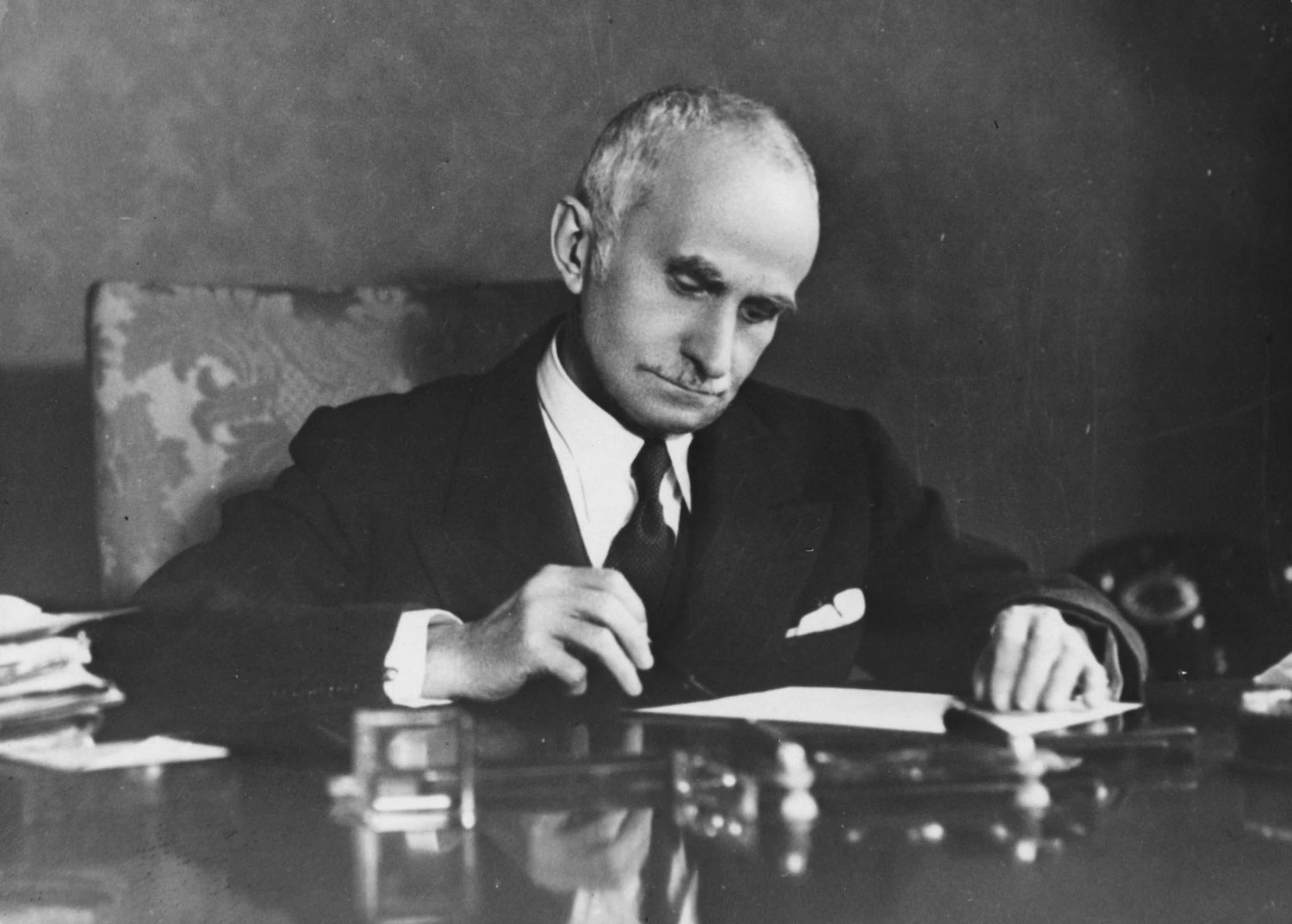 عکس رئیس جمهور لوئیجی آینائودی که پشت میزش نشسته است.