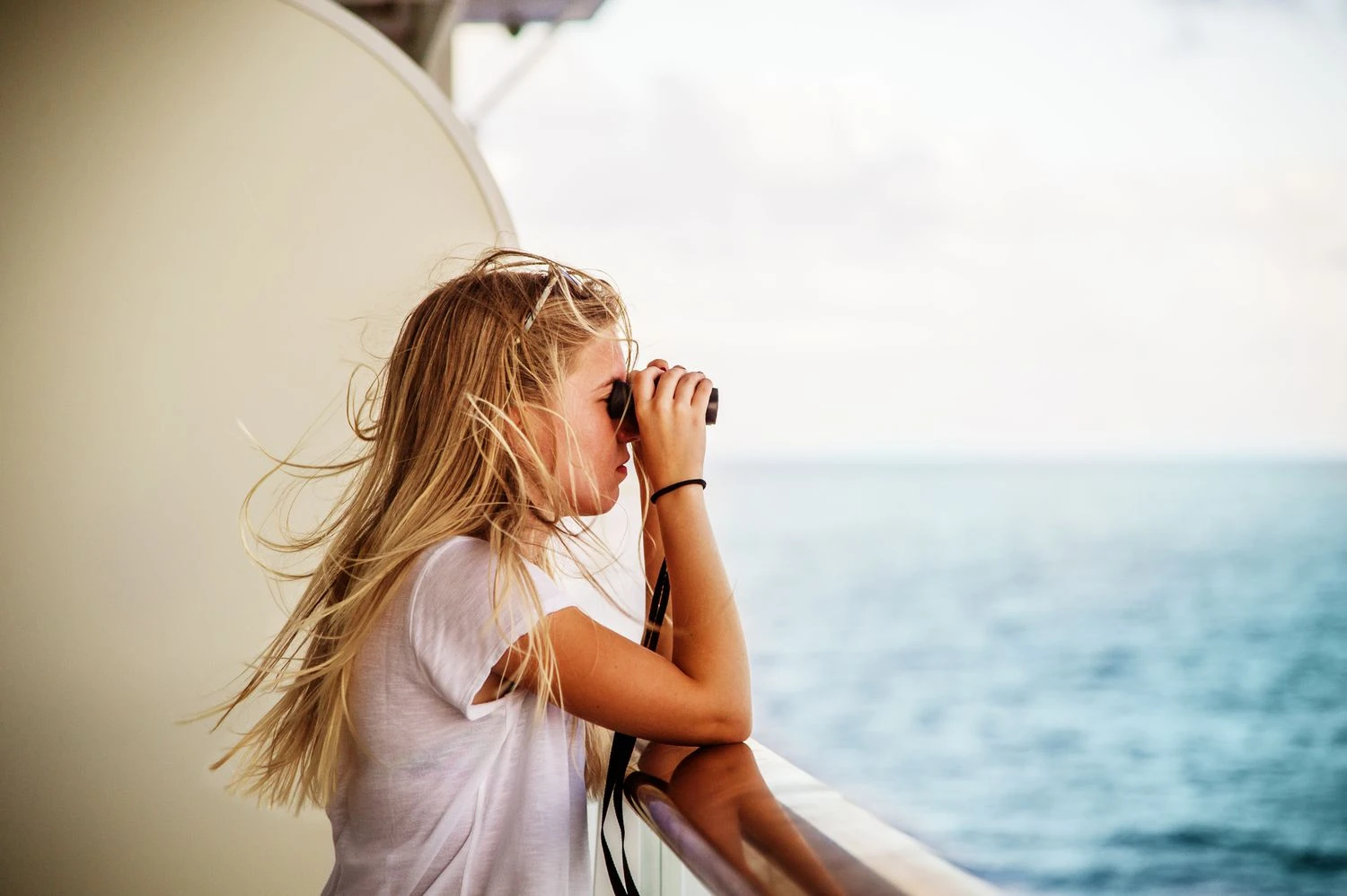 زن جوان با دوربین دوچشمی در کنار نرده کشتی تفریحی