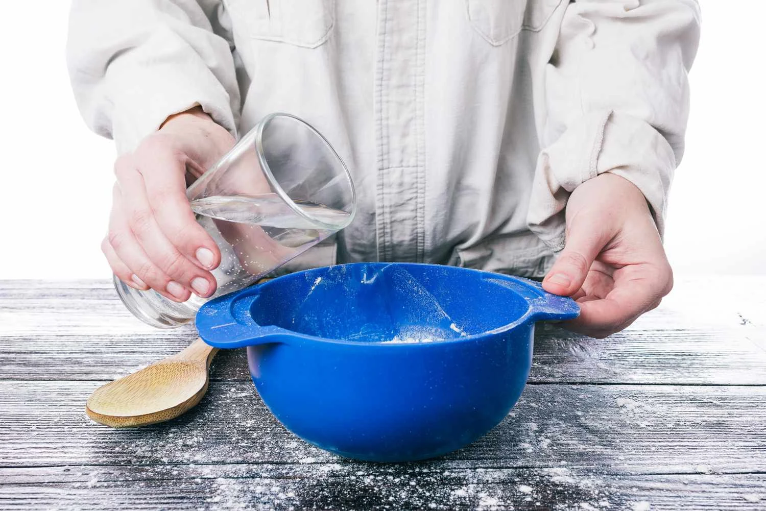 دست های انسان در حال ریختن آب به داخل خمیر