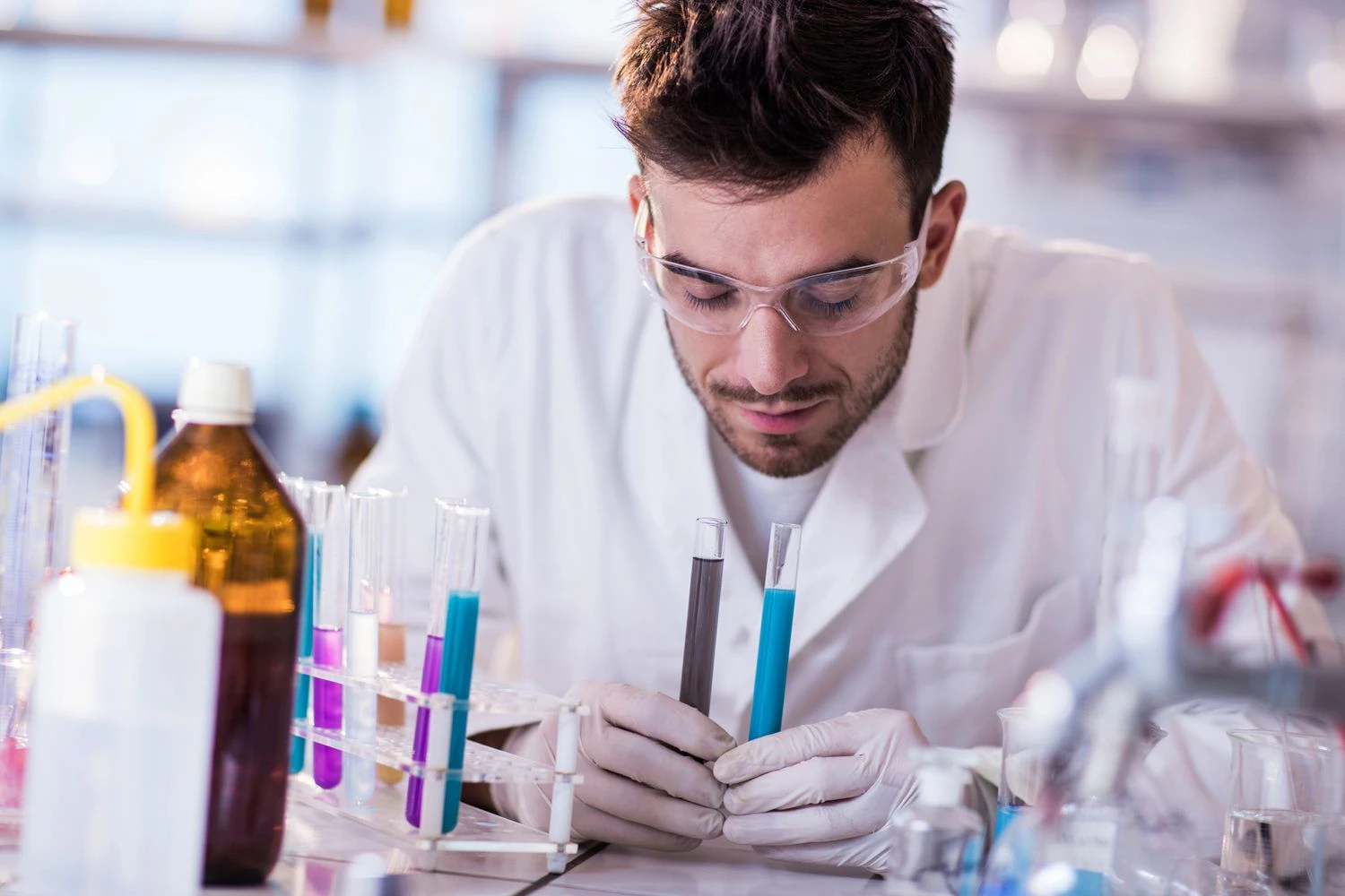 دانشمند جوان در حال بوییدن مواد از لوله های آزمایش.